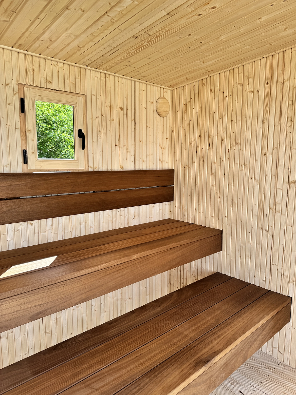 Sauna interior with floating Thermowood benches and an opening window in TAVO Panoramic Sauna