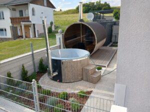 Maudis outdoor hot tub with a 3D Granite insert and integrated wood-fired heater installed beside a barrel sauna. 